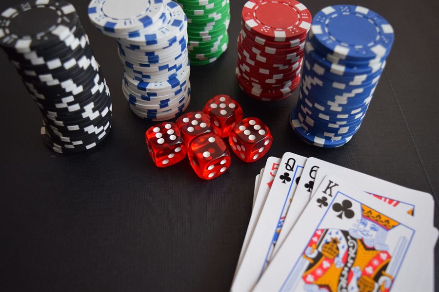 Casino chips, red dice and playing cards on a dark table