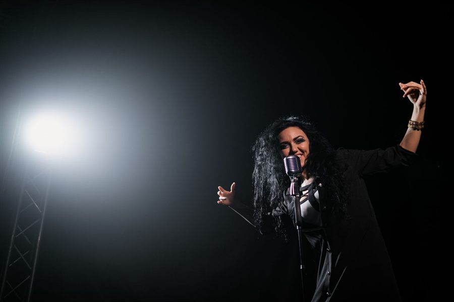 Singer performing under a spotlight on a dark stage